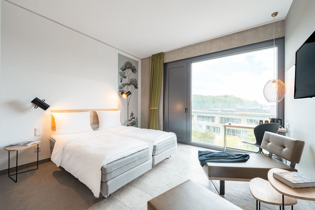 Twin room with two beds and a lounge chair by the window